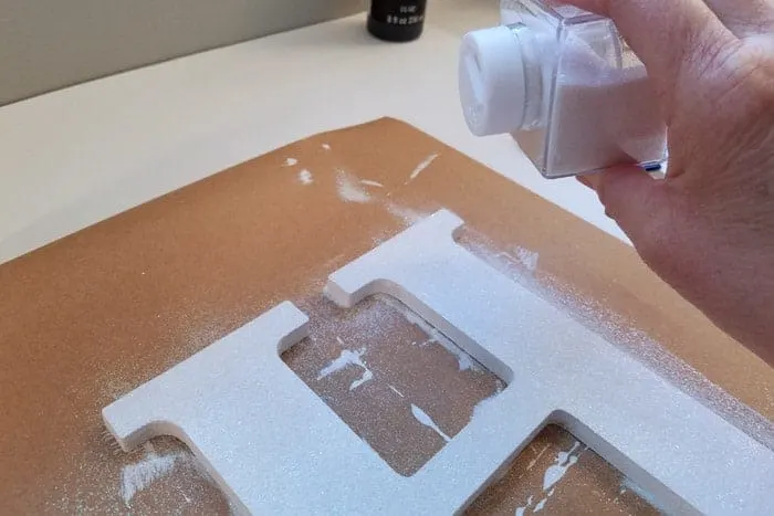 Glitter being added to initial of monogram door hanger.